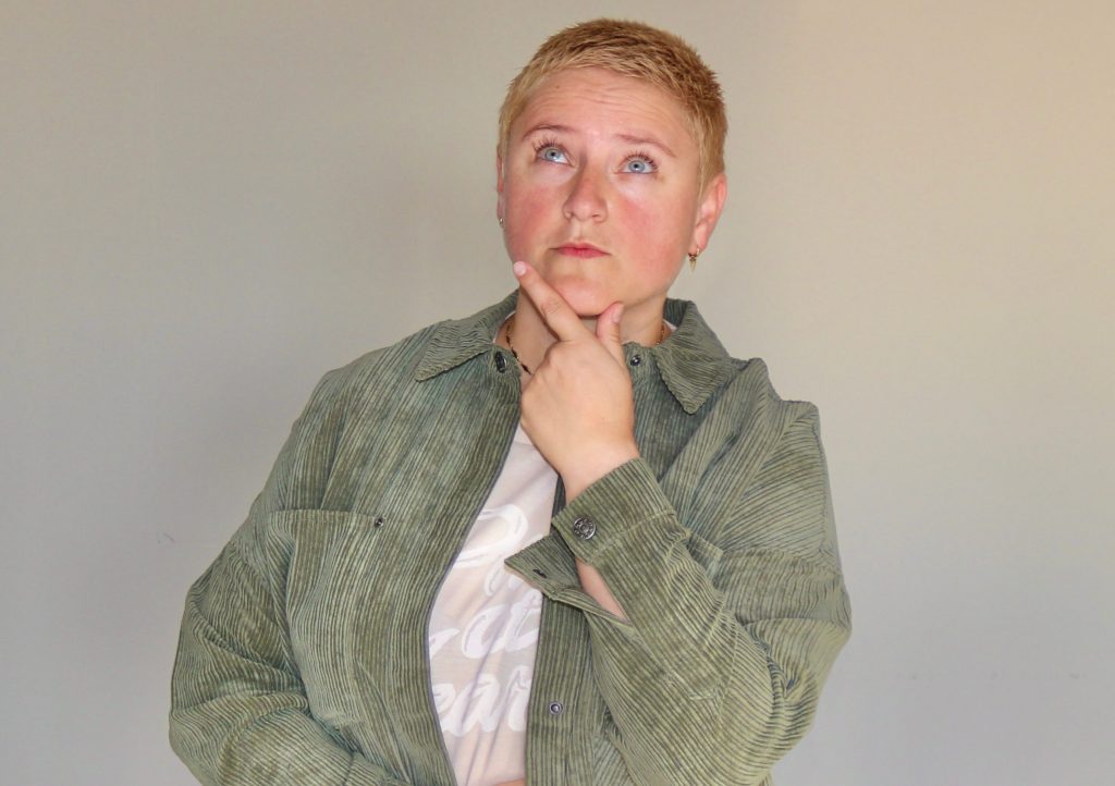 FAQ-Bereich: Coach Bea Schwaiger schaut fragend in die Luft und hält sich die linke Hand ans Kinn.